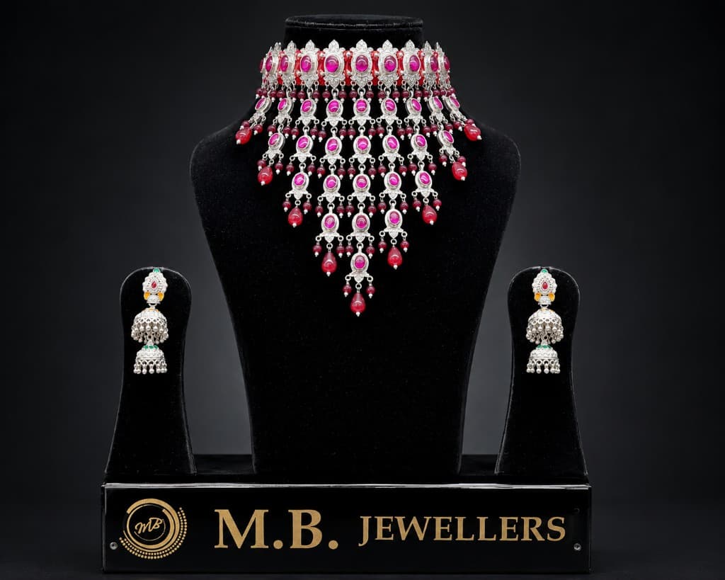 Silver necklace and jhumka earrings on black display with MB Jewellers branding